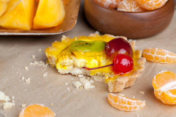 fruit cake with jelly and various fruits, peach, grapes, cherries, next to the cakes tangerines and oranges