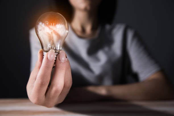 istock young woman holding a light bulb at the table 1361619531