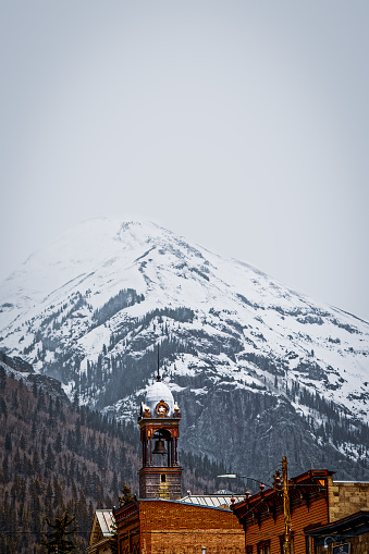 Tower of historic old City Hall in Silverton Colorado in the San Juan Mountains of Colorado CA USA with snowy mountains in the background on overcast day.