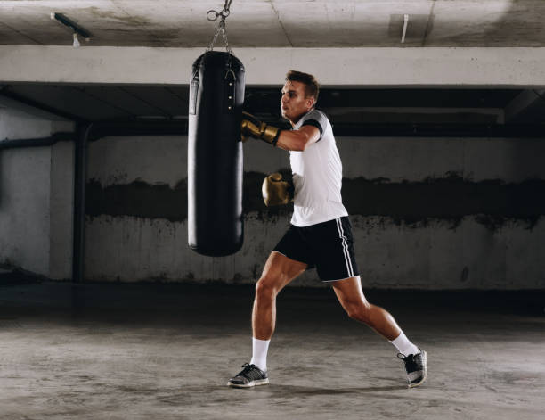 istock Fit professional boxing man kicking at punching bag 1361629071