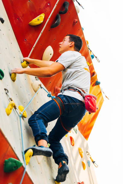 istock Young man climbing artificial rock wall at gym 1361629754