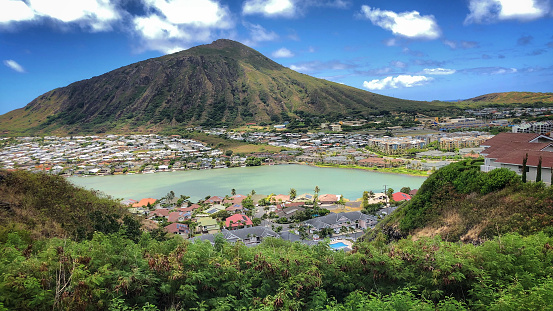High-angle wide shot of a housing development in Oahu, complete with tranquil lagoon and a volcanic mountain