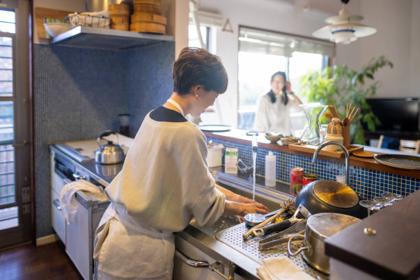 woman washing dishes and talking to friend at home - camel back imagens e fotografias de stock