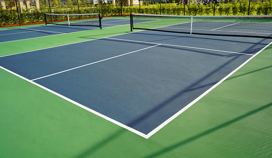 Graphic sports background of yellow tennis ball laying on blue floor in court, copy space