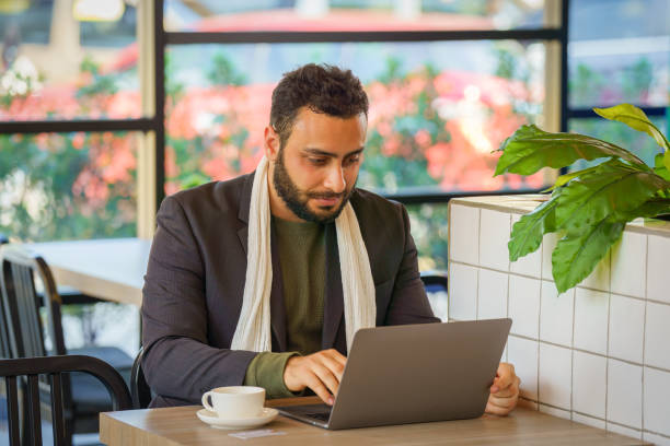 istock businessman sitting in coffee shop working with laptop computer 1361653327