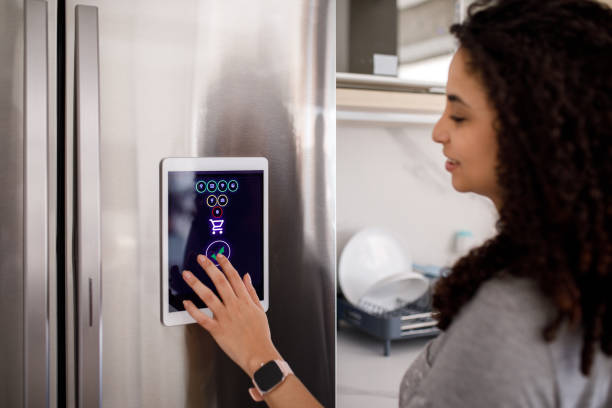 istock Young woman adding items to shopping list using information given by smart fridge 1361654816