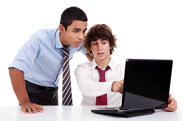 Two young businessmen working together on a laptop stock photo