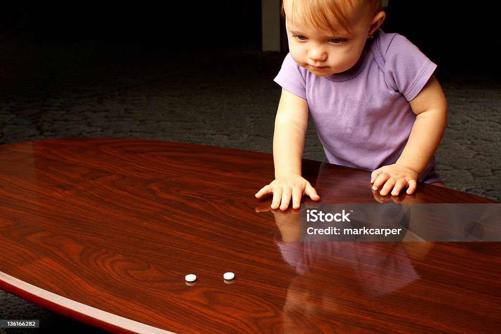 Child Pills Baby reaching across coffee table at white pills 12-17 Months Stock Photo