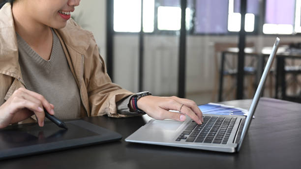 istock Smiling female graphic designer working with laptop and graphic tablet. 1361665427