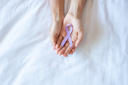 World cancer day (February 4). Woman hand holding Lavender purple ribbon for supporting people living and illness. Healthcare and medical concept