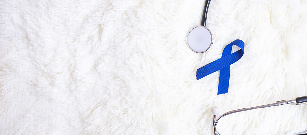 March Colorectal Cancer Awareness month, dark Blue Ribbon with stethoscope on white background for supporting people living and illness. Healthcare, hope and World cancer day concept