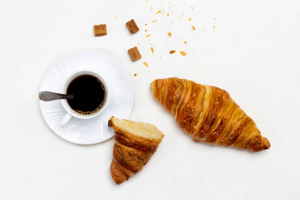 istock Cup of coffee and brown sugar. Croissants on table. 1361678200