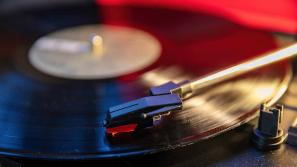 istock Turntable vinyl record player, disco neon light background. Needle on the disc, close up view. 1361682515