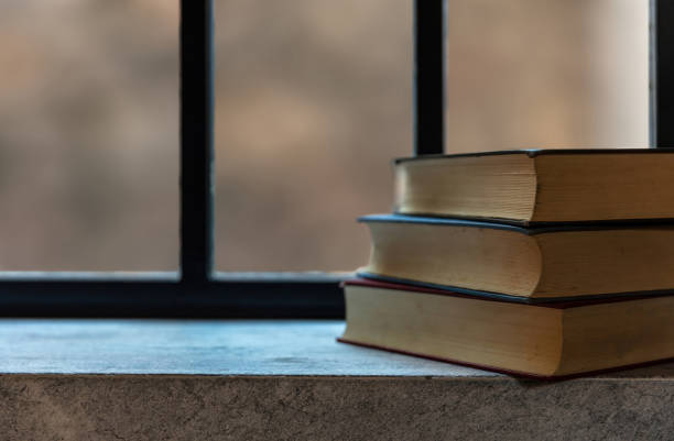 istock Books stack on a window sill. Closed old notebooks on stone shelf background, close up view. 1361682521