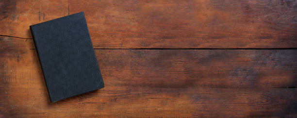 istock Closed old black book on a table. Blank cover notebook on wooden background, top view. Copy space 1361682553