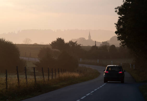 A car on a small country road near a French village in the early morning