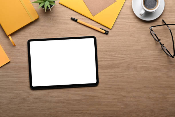 istock Digital tablet with white screen and supplies on wooden table. 1361683692