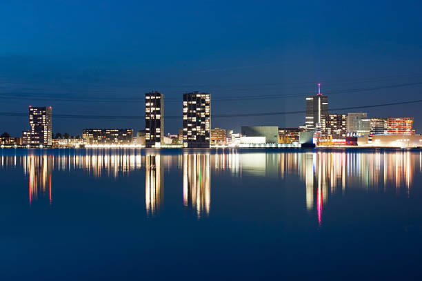 Illuminated skyline at sunset Architecture of a city reflected in water at dusk, Almere, Netherlands flevoland photos stock pictures, royalty-free photos & images