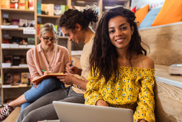istock Portrait of young female student sitting at library reading a book. 1361685341