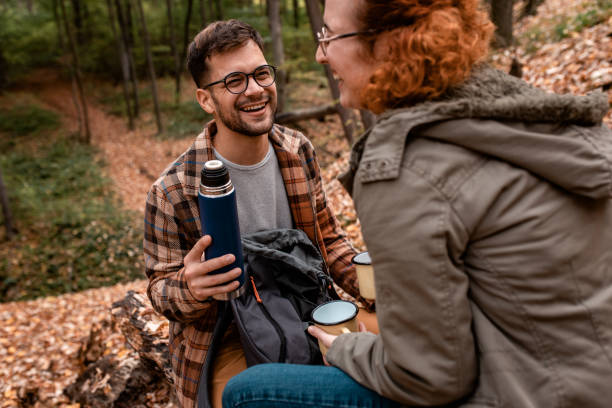 istock Young couple with backpack drinking tea after hiking in forest. 1361689657