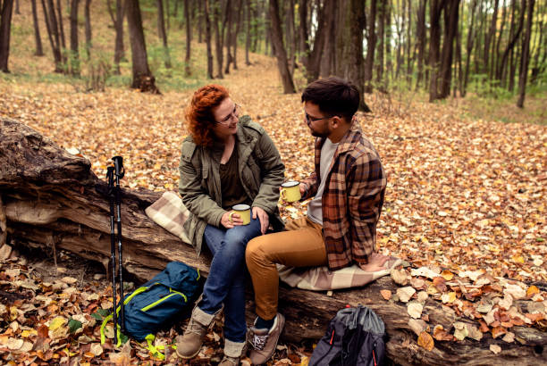istock Young couple with backpack drinking tea after hiking in forest. 1361690364