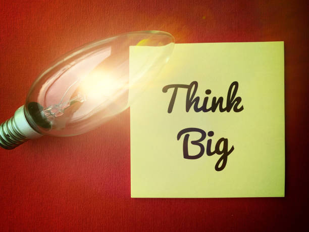 istock Image with motivational quotes, think big on sticky notes with bright shinning bulb and red color background 1361693177