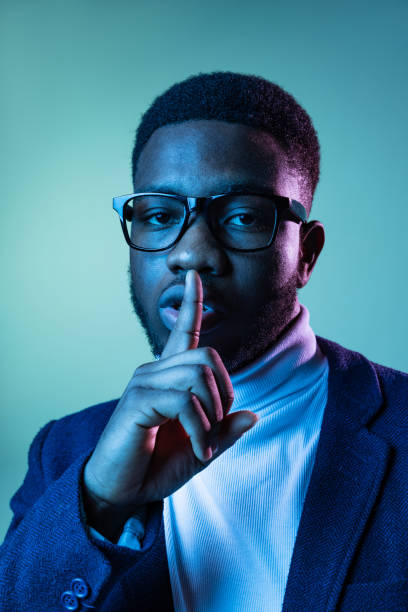 retrato de meio comprimento de jovem homem africano elegante, estudante vestindo pescoço-polo branco e jaqueta isolada em fundo azul em luz de neon. - polo shirt african ethnicity men african descent - fotografias e filmes do acervo