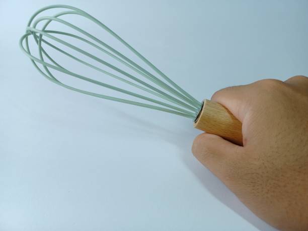 istock Hand holding Green wooden eggbeater on white background 1361698070