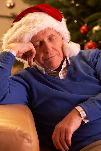 istock Tired Senior Man Relaxing In Front Of Christmas Tree 136169815