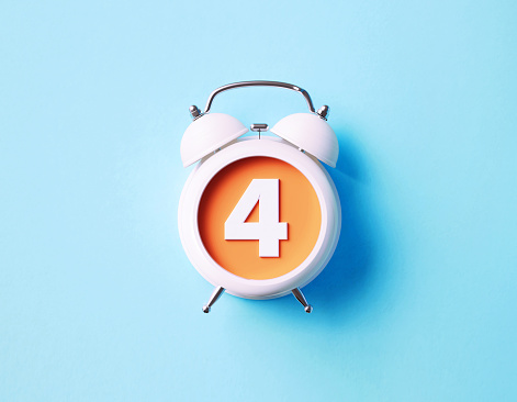 Number four sitting over white alarm clock on blue background. Horizontal composition with copy space.