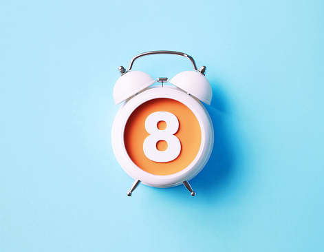 Number eight sitting over white alarm clock on blue background. Horizontal composition with copy space.