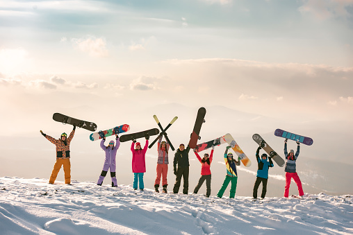 Big group of happy friends skiers and snowboarders at ski resort. Diverse young peoples at winter holidays