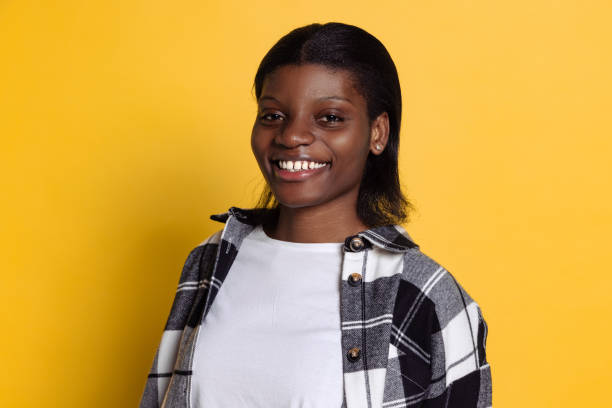 istock Cheerful young beautiful dark skinned girl looking at camera isolated on yellow studio background. 1361701163