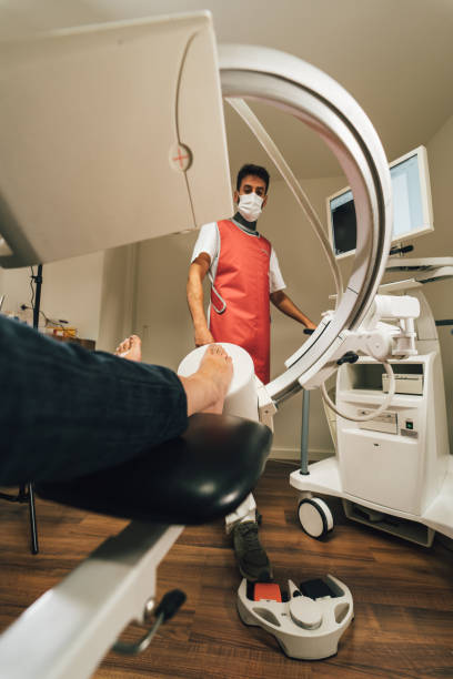 хироподист делает диагноз стопы с помощью рентгеновского аппарата в медицинском центре - podiatrist podiatry pedicure chiropodist стоковые фото и изображения