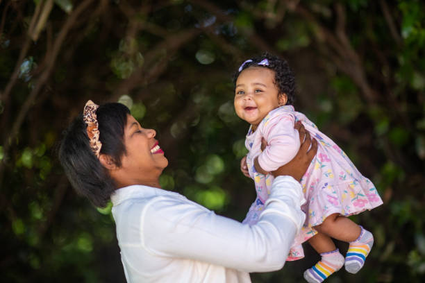 istock Young mother holding cute young baby outdoors having fun side view smiling 1361708701