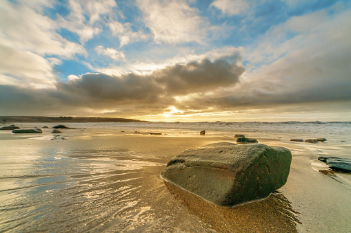 Wet stone on the shore in the beach on stormy sunset. Ireland.