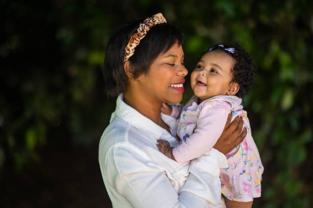 istock Young mother holding cute young smiling baby close outdoors having fun 1361708890