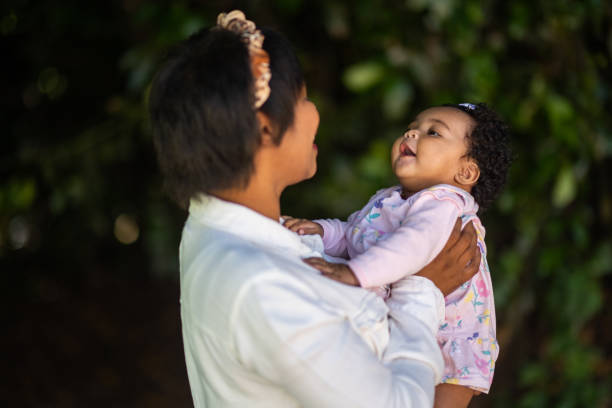 istock Young mother holding cute young smiling baby outdoors having fun looking at one another 1361708931