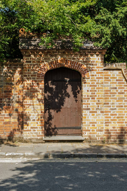 Garden Gate in brick wall A wooden garden gate in the arch of a brick wall. walled garden stock pictures, royalty-free photos & images