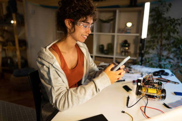 istock Proud female robotic engineer successfully connected her robotic car prototype with the open-source hardware and software software platform on her mobile phone 1361713555
