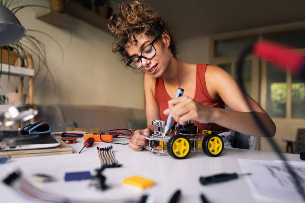 Female programmer with a passion for robotic engineering, making a prototype of an autonomous self-drive robotic car with sensors