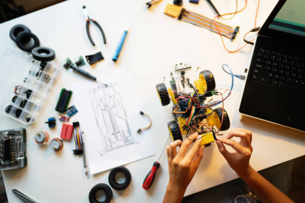 istock Unrecognizable female programmer, connecting cables of the autonomous self-driving robotic car with sensors with the motherboard in her creative home office 1361714767