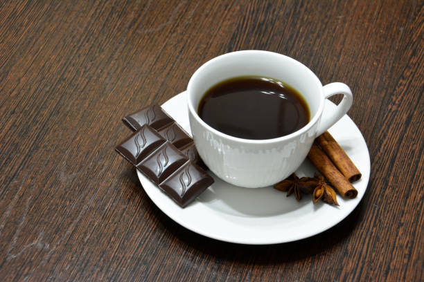 taza de café blanco con canela, chocolate y badian sobre fondo de madera oscura - badian fotografías e imágenes de stock