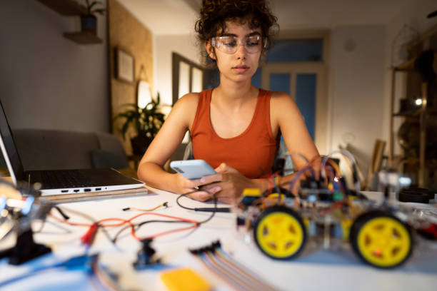 istock Female programmer, working late at night, testing her prototype of the smartphone-controlled autonomous self-driven robotic car with sensors 1361715125