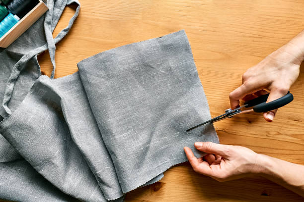 Woman's hands cutting out a pattern paper in linen fabric. Seamstress sewing on sewing machine in small studio. Fashion atelier, tailoring, handmade clothes concept. Slow Fashion Conscious consumption Woman's hands cutting out a pattern paper in linen fabric. Seamstress sewing on sewing machine in small studio. Fashion atelier, tailoring, handmade clothes concept. Slow Fashion Conscious consumption clothing swap photos stock pictures, royalty-free photos & images