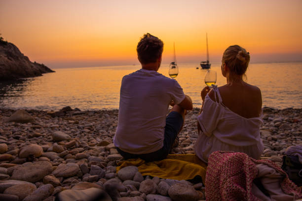 pareja tomando una copa de vino en la playa al atardecer, isla de elba, italia. - portoferraio fotografías e imágenes de stock