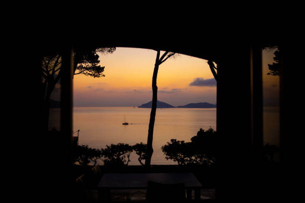 velero navegando por el mar mediterráneo a lo largo de la costa de la isla de elba al atardecer, italia. - portoferraio fotografías e imágenes de stock