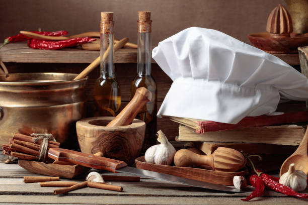 istock Chef's hat, vintage cookbooks, and old kitchen utensils on the kitchen table. 1361721839