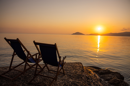 View of two beach chairs along the coast facing the Mediterranean sea at sunset on Elba Island, Tuscany, Italy.