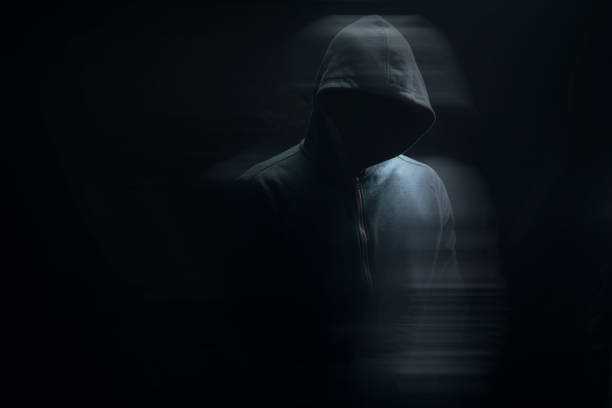 istock a man in a hood stands on a black background 1361723522